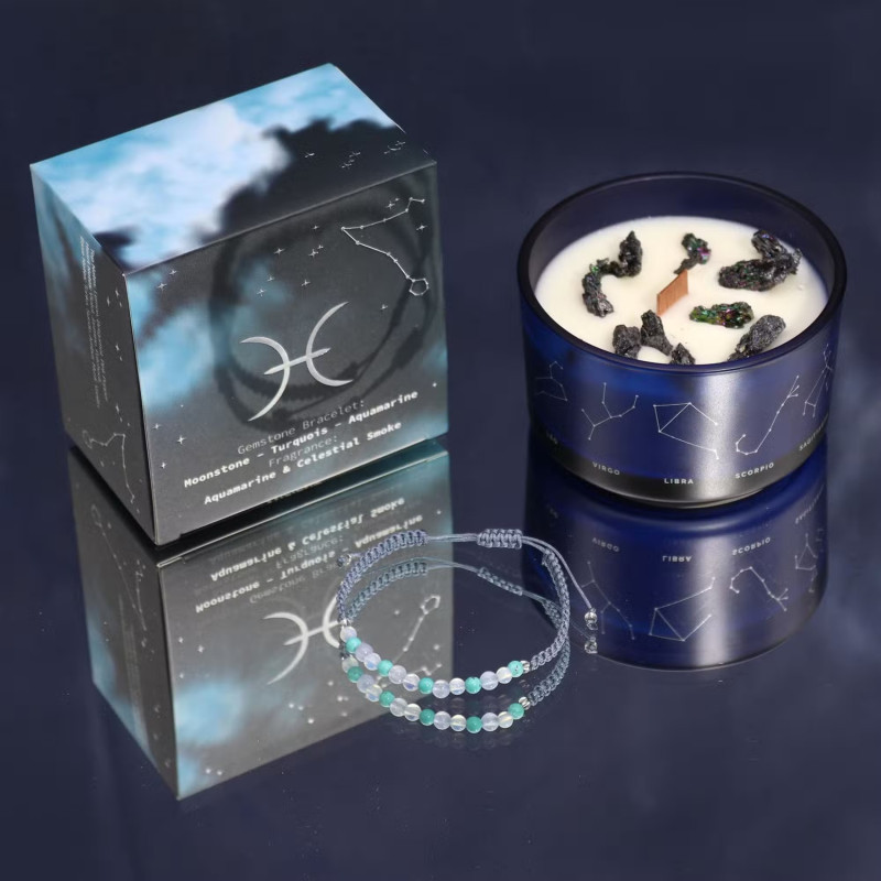 Vela energética del zodiaco Piscis con pulsera de piedras preciosas y vaso de vidrio azul con constelaciones.