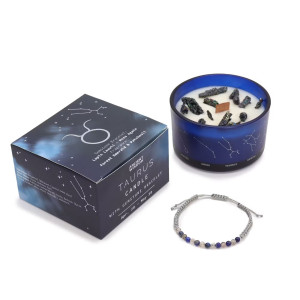 Vela energética del zodiaco Tauro con pulsera de piedras preciosas y vaso de vidrio azul con constelaciones.