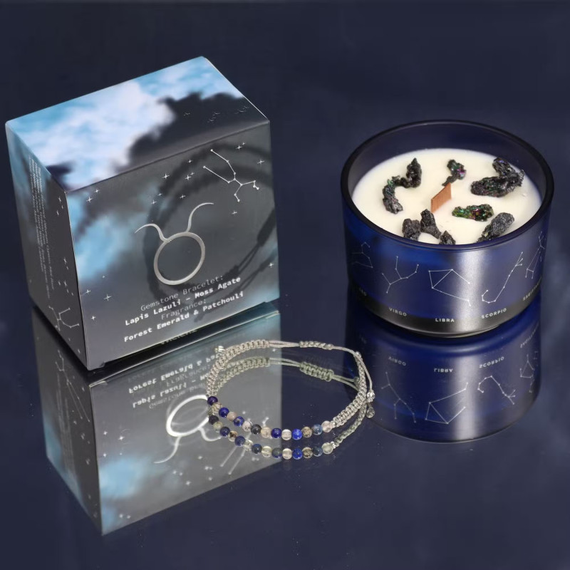 Vela energética del zodiaco Tauro con pulsera de piedras preciosas y vaso de vidrio azul con constelaciones.