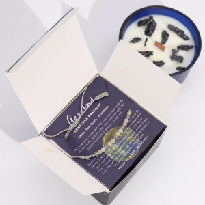 Vela energética del zodiaco Géminis con pulsera de piedras preciosas y vaso de vidrio azul con constelaciones.