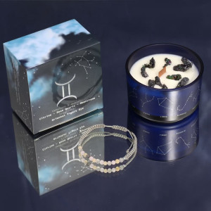 Vela energética del zodiaco Géminis con pulsera de piedras preciosas y vaso de vidrio azul con constelaciones.