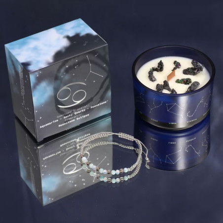 Vela energética del zodiaco Cáncer en vaso de cristal azul con símbolos zodiacales y pulsera de piedras.