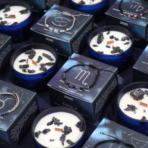 Composición de varias velas energéticas del zodiaco Escorpio con pulseras de piedras preciosas, presentadas juntas.