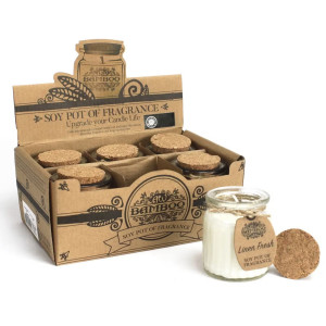 Vela artesanal en bote de cristal abierta con cera clara visible.