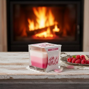 Vela arcoíris en envase de cristal abierta con cera clara visible.