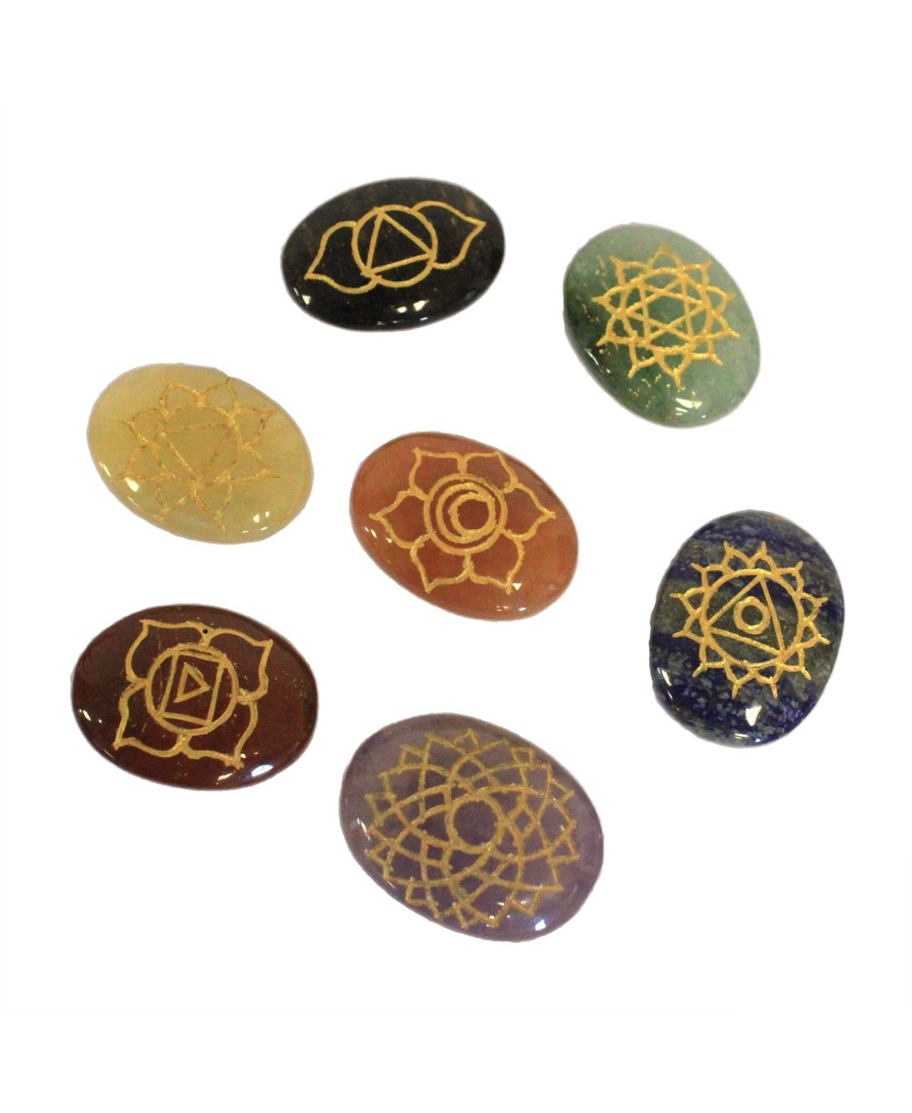 Set de siete piedras naturales ovaladas grabadas con símbolos de chakras para meditación y bienestar.