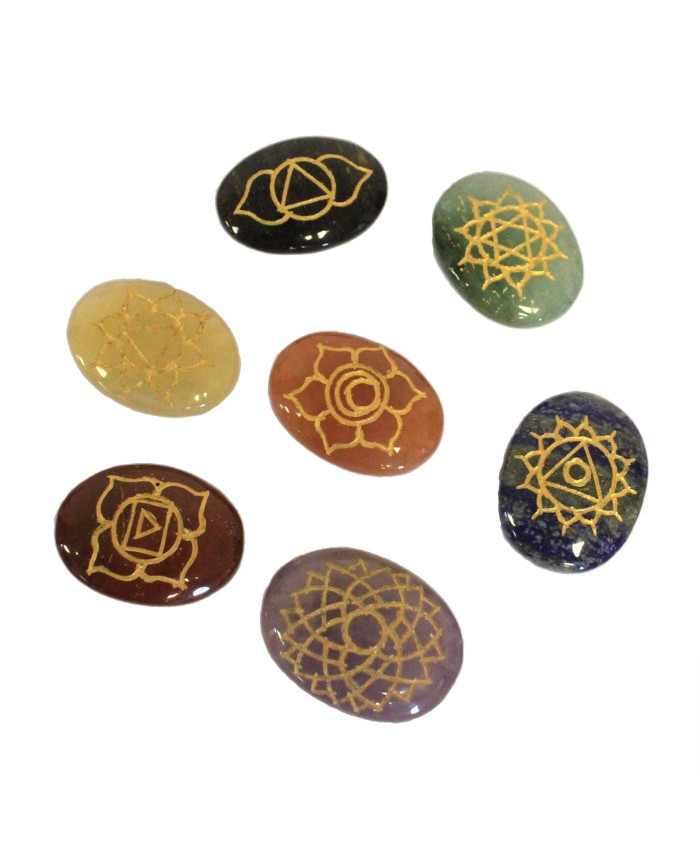 Set de siete piedras naturales ovaladas grabadas con símbolos de chakras para meditación y bienestar.