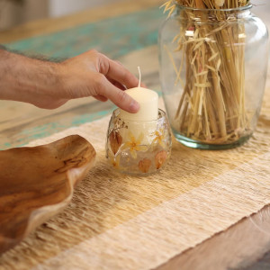 Vista superior del portavelas pequeño de vidrio reciclado con flores prensadas.