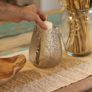 Portavelas mediano de vidrio reciclado con hojas de helecho y ramas naturales colocación de la vela.