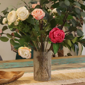 Portavelas grande de vidrio reciclado con hojas de helecho prensadas y ramas tipo pino con flores.