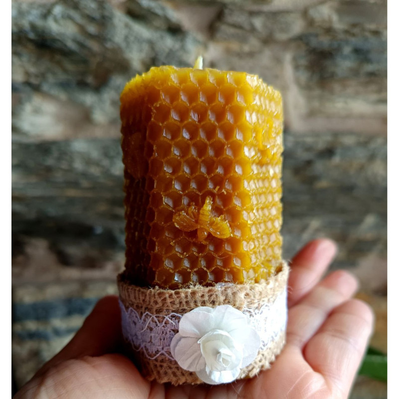 Vela decorativa de cera de abeja natural con textura de panal y base rústica para uso en el hogar.