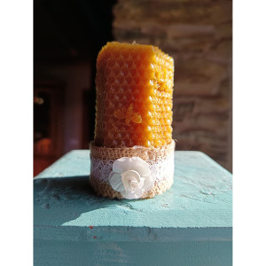 Vela decorativa de cera de abeja natural con textura de panal y base rústica para uso en el hogar.