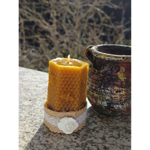 Vela decorativa de cera de abeja natural presentada sobre superficie rústica como elemento decorativo.