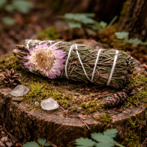 Atado herbal artesanal con flor decorativa natural.