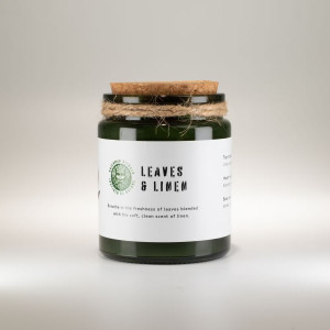 Vela de soja aromática hojas y lino en tarro de vidrio verde con tapa de corcho.