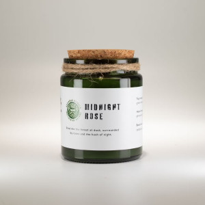 Vela de soja aromática rosa de medianoche en frasco de vidrio verde con tapa de corcho.