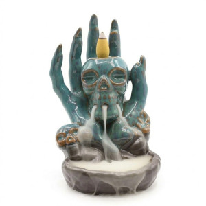 Quemador de incienso de cerámica con calavera sostenida por una mano para flujo inverso.