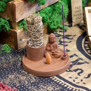 Soporte multiusos de cerámica azul con buda, varilla de incienso y sahumerio colocado para uso aromático.