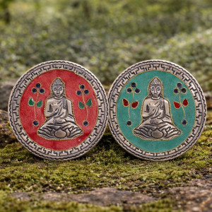 Soporte de incienso con figura de buda en metal para varillas y conos sobre base decorativa redonda en tonos verde o rojo.