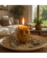 Vela de buho con la mecha encendida con decoración de plantas.
