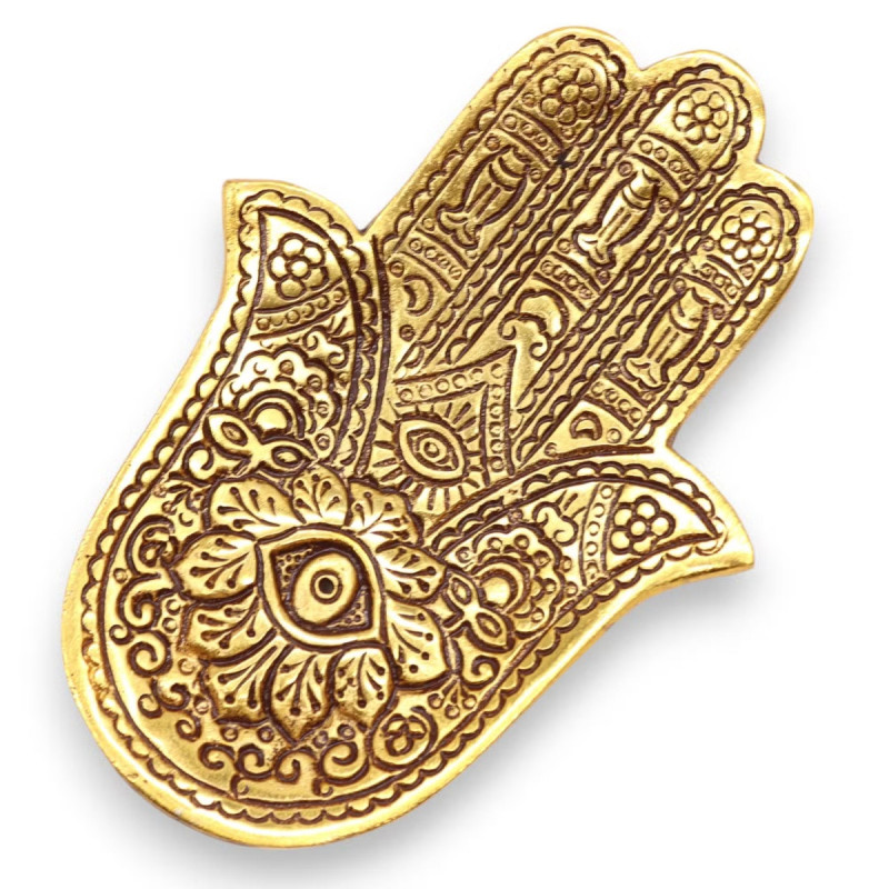 Portainciensos hamsa dorado de metal para varillas con grabado decorativo sobre superficie clara.