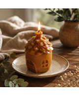 Vela casita de cera de abeja natural con mecha encendida.