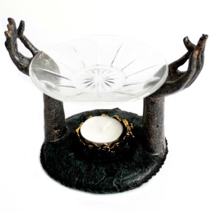 Quemador de aceite con soporte en forma de manos y cuenco de vidrio para aromaterapia.