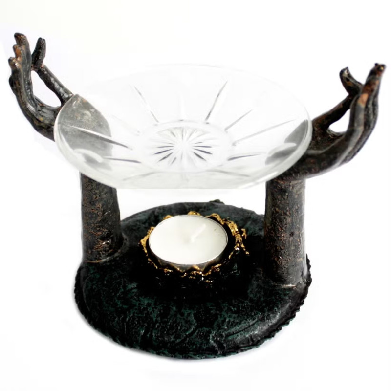 Quemador de aceite con soporte en forma de manos y cuenco de vidrio para aromaterapia.