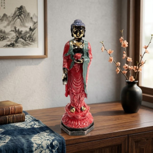 Figura de buda de pie con túnica roja y detalles dorados sobre base decorativa.