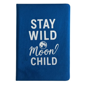 Cuaderno de terciopelo azul oscuro con el mensaje Stay Wild Moon Child captado en un ambiente cálido y moderno.
